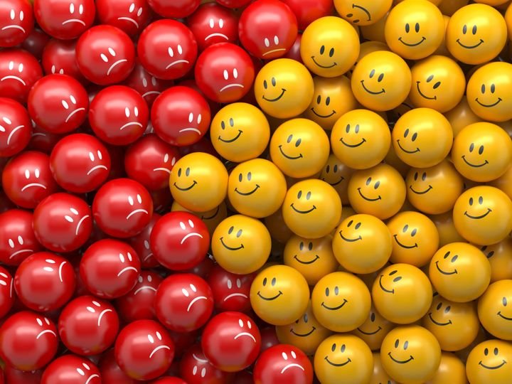 Red and yellow smiley faces fill the frame, creating a vibrant contrast between happy and sad expressions.