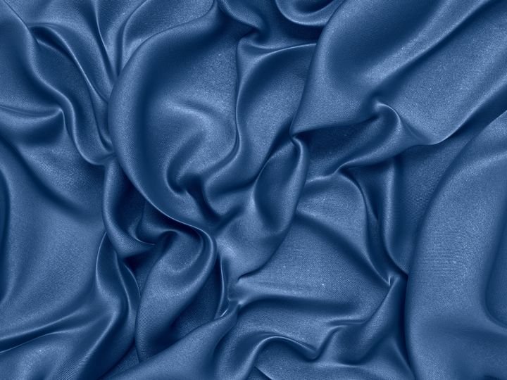 Deep blue satin fabric drapes in soft, flowing folds, creating a luxurious and elegant texture.