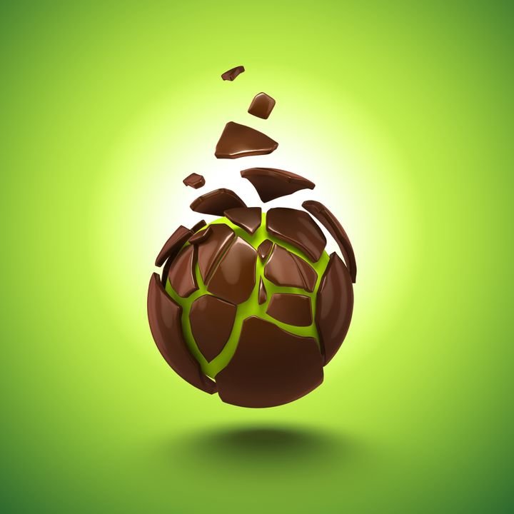 A chocolate sphere shatters into pieces, revealing a vibrant green core against a bright green background.