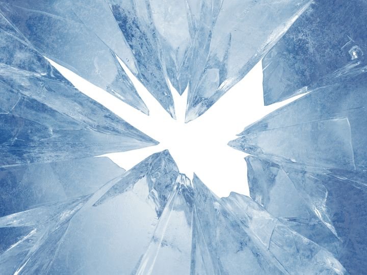 A shattered glass surface radiates from a bright center, creating sharp, jagged fragments in cool blue tones.