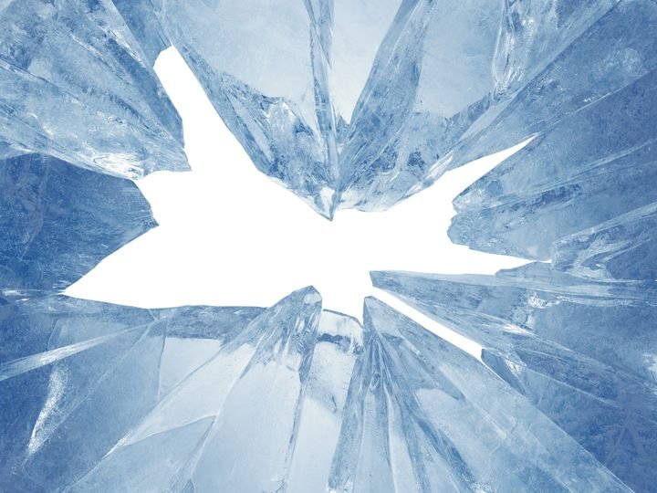 A shattered glass surface reveals a bright white center, surrounded by jagged blue shards.
