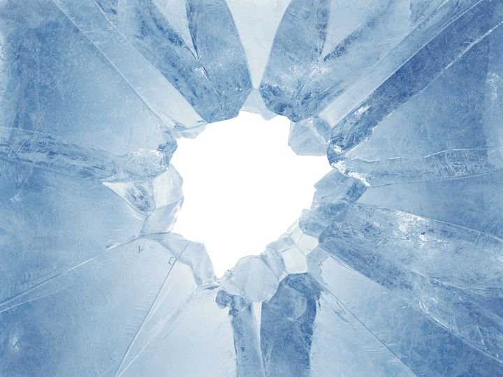 A shattered glass surface radiates from a bright center, creating sharp, jagged fragments.