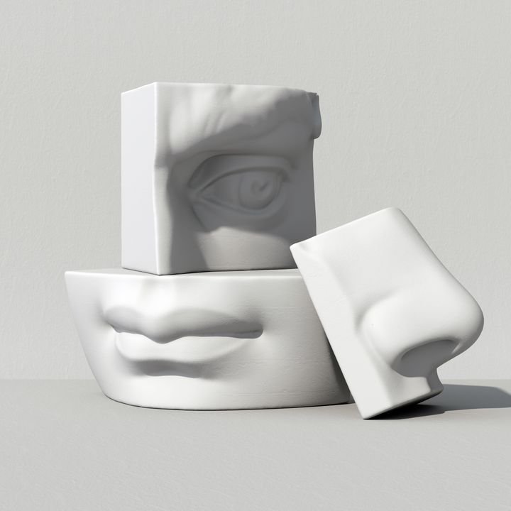 Three white sculpted face parts stack on a gray surface, casting soft shadows.