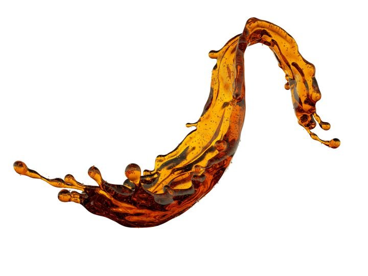 A dynamic splash of amber liquid curves upward, capturing motion with droplets flying off against a stark white background.