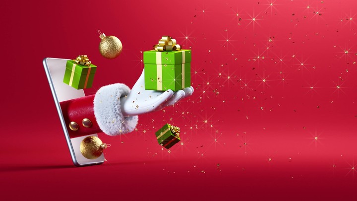 3d render. Cartoon character Santa Claus hand appears from the mobile phone screen and holds green gift box, festive ornaments levitate. Christmas animation with red background and golden confetti