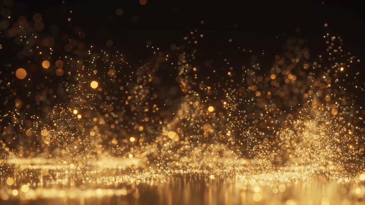 Golden glitter and sparkling dust particles floating in the air with a soft bokeh light. A luxurious abstract motion background.